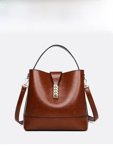 Detail of dark brown leather bucket bag with gold chain hardware and smooth waxy texture