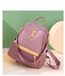 Detail view of purple nylon backpack with cream leather trim and gold zippers