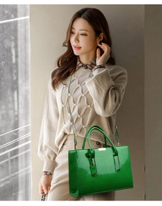 Detail of lime green faux crocodile leather tote bag with sturdy handles and gold hardware