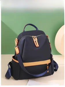 Detail of navy nylon backpack showing gold metal zippers and red edge contrast stitching