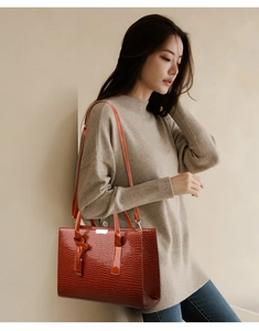 Detail of dark red crocodile pattern tote bag with polished finish and metal hardware