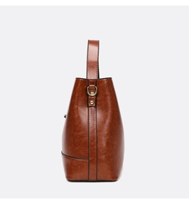 Detail view of the retro brown leather bucket bag with shiny texture and golden D-ring buckle