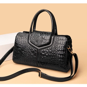 Detail of black crocodile-embossed leather handbag with gold-tone hardware and Y-stitching