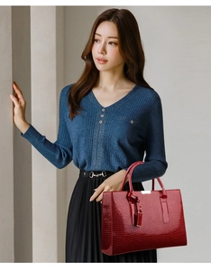 Elegant red crocodile pattern handbag held by a model in a luxury business attire