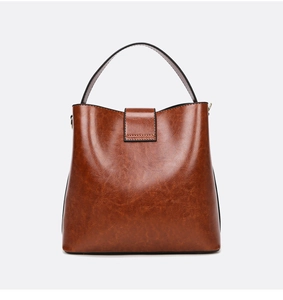 Close-up of caramel brown bucket bag with oil-wax leather texture and metal accents