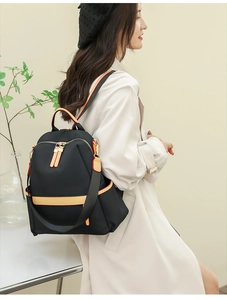 Detail of waterproof nylon backpack with contrasting orange trim and gold-tone metal zippers