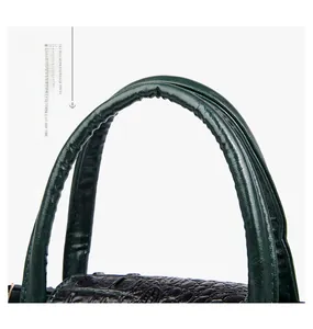 Close-up of deep green crocodile embossed leather texture and sturdy padded handle