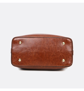 Detailed bottom view of brown leather bag with four gold protective metal feet and texture