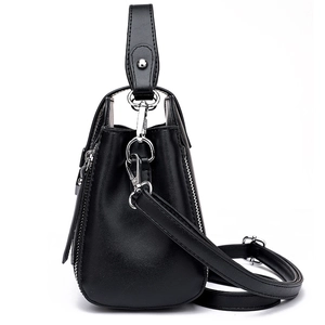 Minimalist black leather bucket bag with side zipper detail and adjustable strap