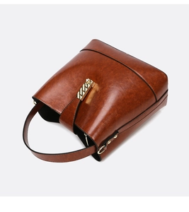Detail of dark brown vintage bucket bag with retro leather texture and golden metal lock