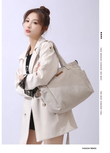 Detail of minimalist cream canvas tote bag with brown leather label and spacious side pocket