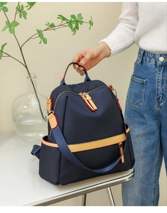 Detailed close-up of dark blue waterproof nylon backpack with yellow zipper accents