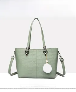 Front view of green crocodile-embossed bucket bag with pearl charm and shoulder strap