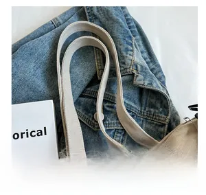 Close-up of beige canvas tote bag showing wide shoulder strap and durable stitching detail