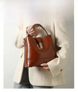 Close-up of brown glossy oil wax leather handbag with golden lock and model display