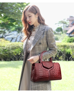 Outdoor lifestyle shot of a wine red tote bag with elegant crocodile pattern texture