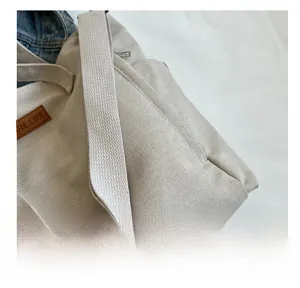 Detailed close-up of beige canvas fabric with brown leather logo tag and silver zipper