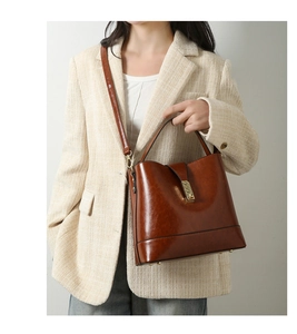 Brown vintage oil-wax leather bucket bag with gold metal buckle shown on a model