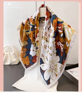 Detailansicht eines geblümten Seidenschals mit orange-blauen Blüten auf weißem Stoff