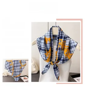 Detail of blue plaid silk scarf with yellow floral print hanging on a hanger