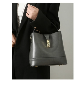 Detail of dark grey leather bucket bag featuring a gold lock and textured finish