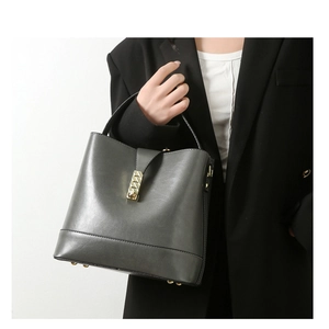 Detail of grey bucket bag showing premium leather texture and golden metal hardware