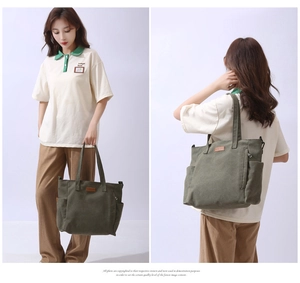 Detail of olive green canvas tote bag showing front zipper pocket and leather logo patch