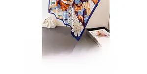 Nahaufnahme eines Seidenschals mit floralem Muster in Orange und dunkelblauem Randdekor