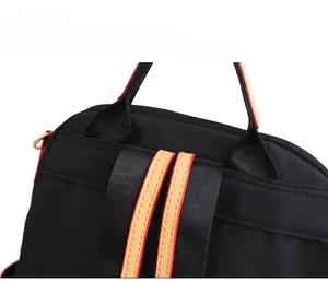 Detail of neat stitching on black nylon backpack with yellow leather accents and red piping