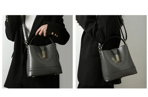 Detail view of dark grey bucket bag showing golden chain buckle and metal foot studs