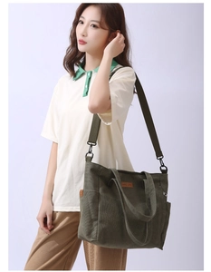 Detail view of large army green canvas tote bag featuring adjustable strap and logo patch