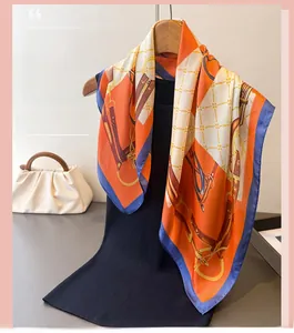 Detail of equestrian print silk scarf with classic orange horsebit patterns on black fabric