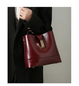 Detail of burgundy glossy tote bag with gold hardware and protective metal feet