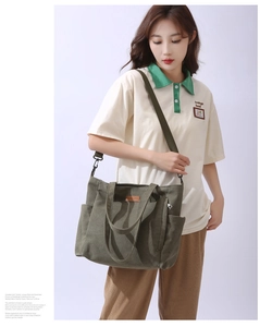 Detail of olive green canvas tote bag with brown leather logo and side pocket