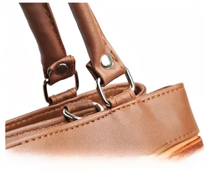 Detailed macro view of the silver metal ring buckle and stitching on brown leather bag