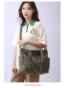 Detail view of large green canvas tote bag featuring adjustable strap and leather logo patch