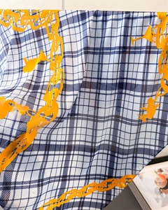 Macro detail of plaid silk scarf with orange chain print and translucent texture