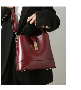 Detail of wine red bucket bag in glossy patent leather with vintage cloud texture and gold lock