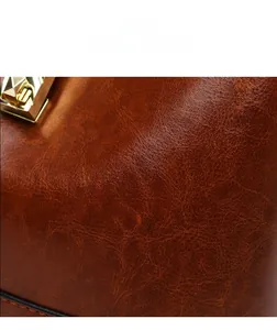 Detailed close-up of dark brown oil wax leather bag with elegant golden metal buckle