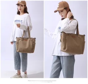 Close-up of brown canvas tote bag featuring leather logo patch and dual top handles