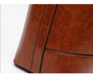 Detailed macro view of dark brown oil wax leather texture and black stitching on a handbag
