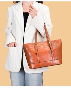 Detailansicht der Kroko-Prägung und des Metalllogos auf der karamellbraunen Shopper-Tasche