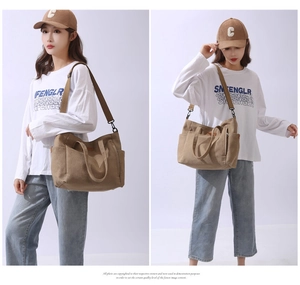 Detail view of large canvas tote bag with adjustable shoulder strap and metal zip pocket