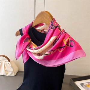Detail of luxury chain print silk scarf tied on a hanger with rose pink accents