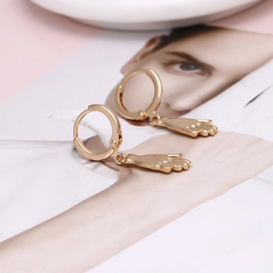 Boucles d'oreilles créoles dorées avec pendentif main baroque sur un magazine
