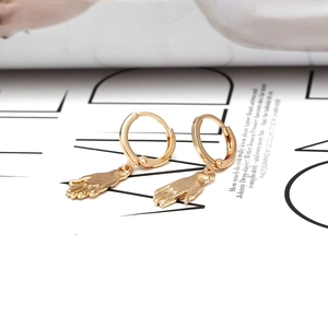 Vue détaillée de boucles d'oreilles dorées en forme de paume sur un fond de magazine