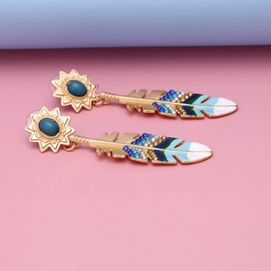 Close-up of golden sunflower earring with colorful enamel feather pendant and blue stone