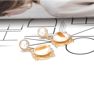 Boucles d'oreilles perles baroques et disques dorés martelés sur fond de magazine