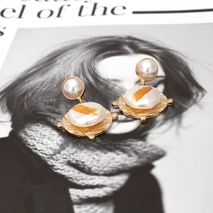 Détail de boucles d'oreilles perles baroques avec texture dorée martelée et résine d'art