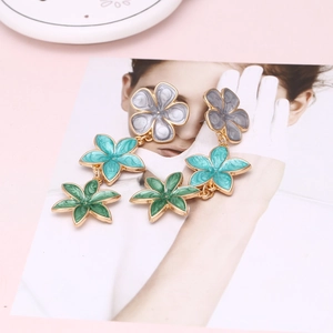 Detail of colorful layered floral drop earrings with gold edges on an artistic card